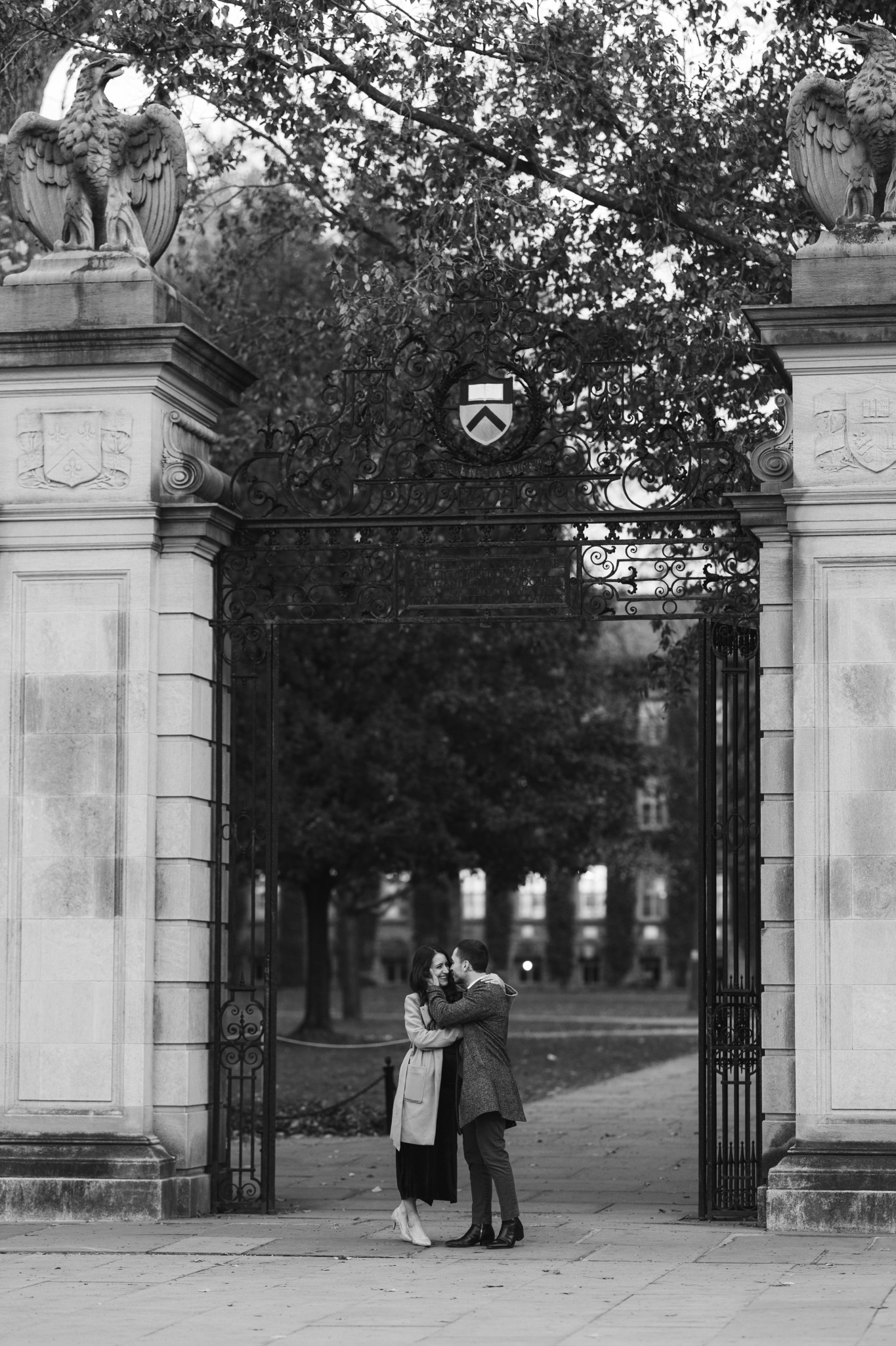 Briana and Israel embracing beneath an ornate university gate
